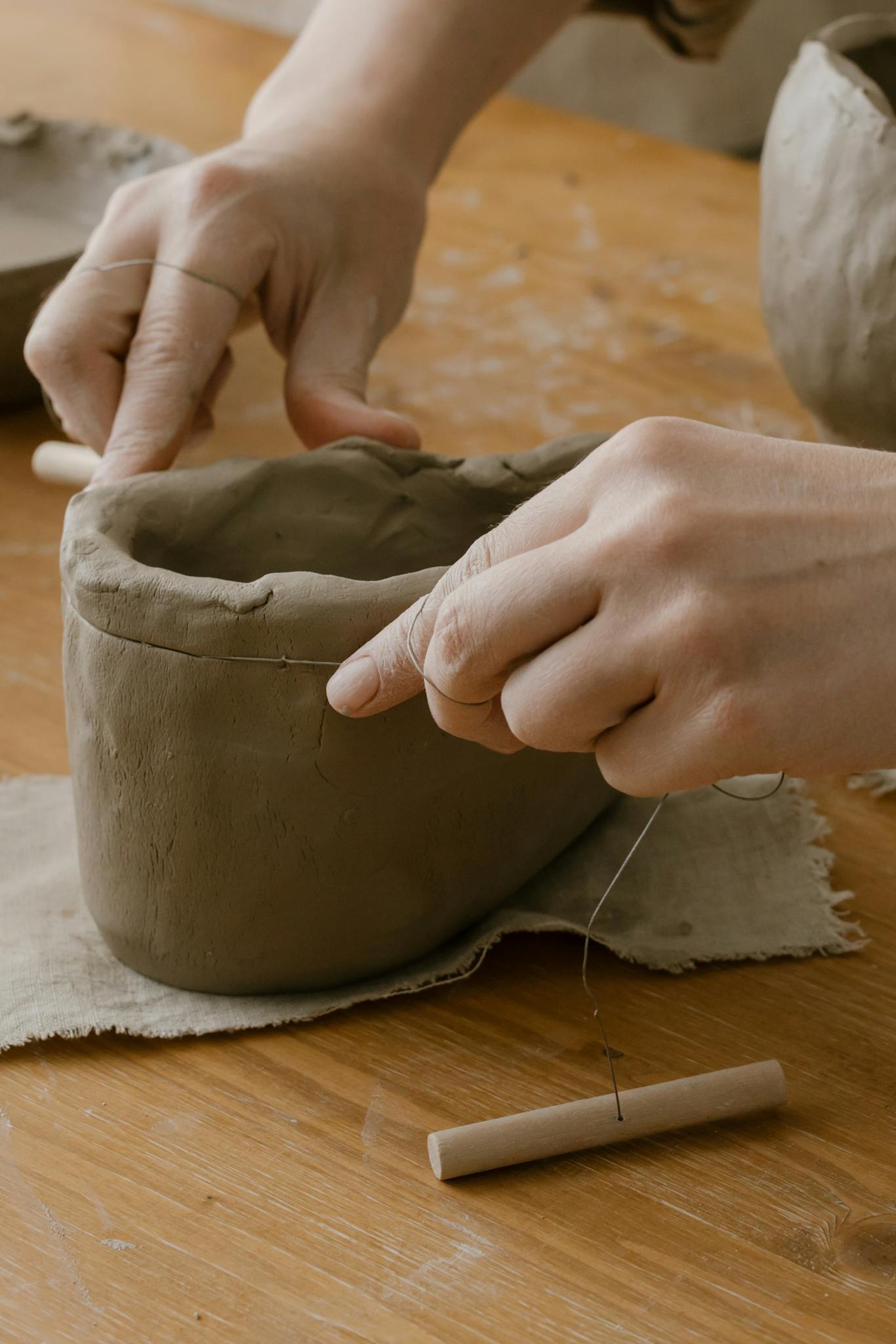 Close-up of hands shaping clay pottery with sculpting tools in a workshop.