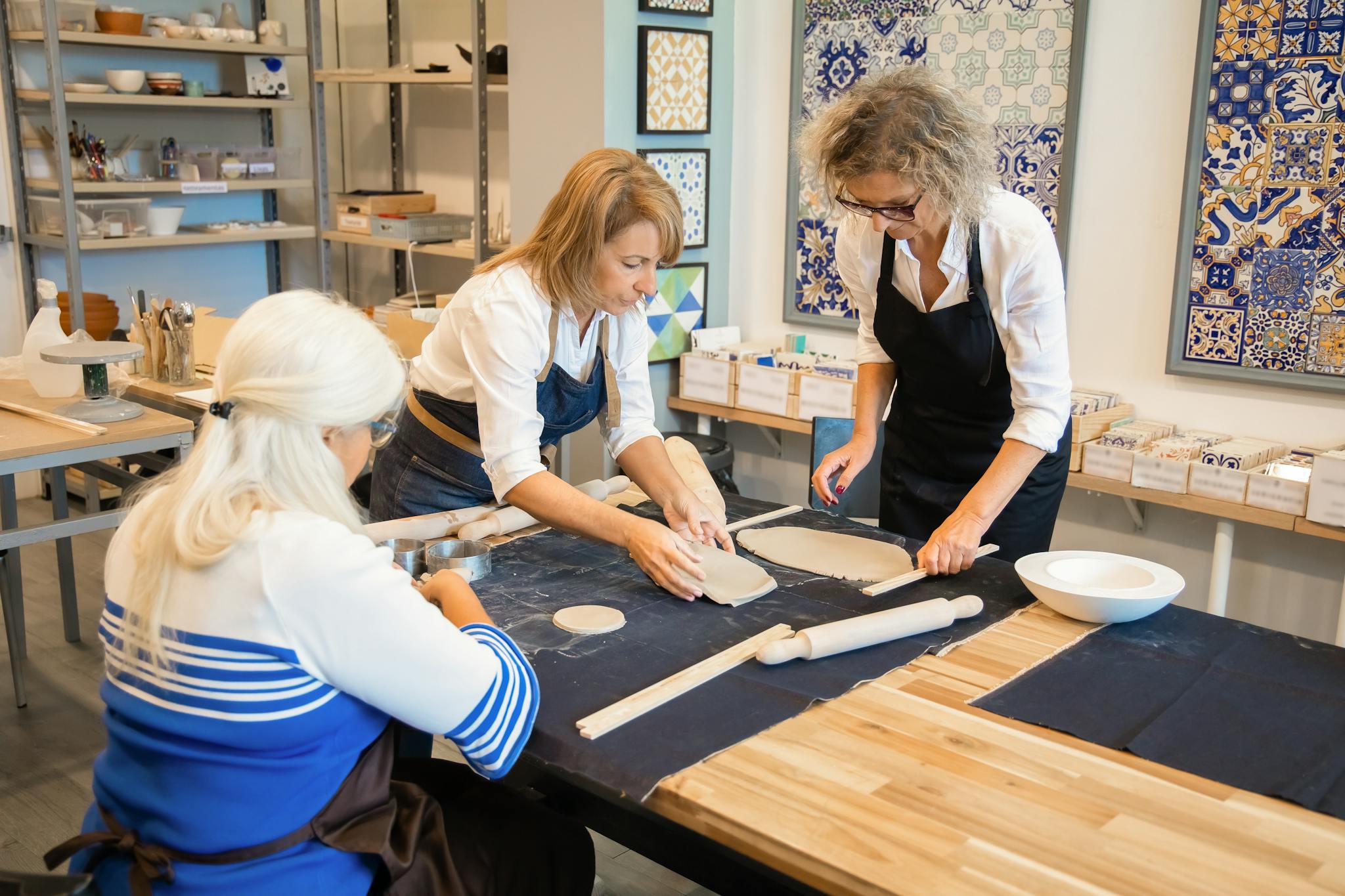 Three women engaged in pottery making at an indoor studio in Portugal.